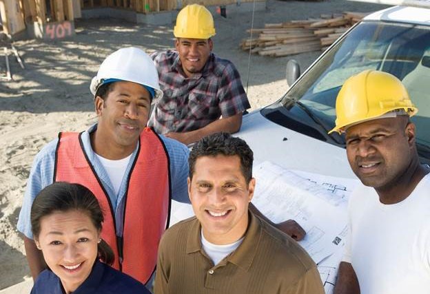 Four men and one woman, standing near a white vehicle on a construction site.